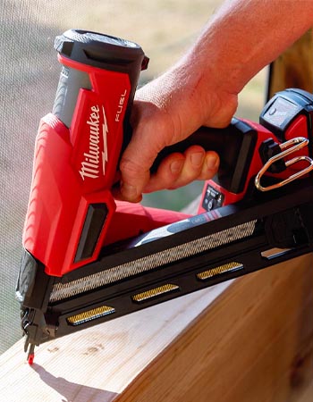 A person using the Milwaukee 15-Gauge Finish Nailer to attach window trim in a porch.