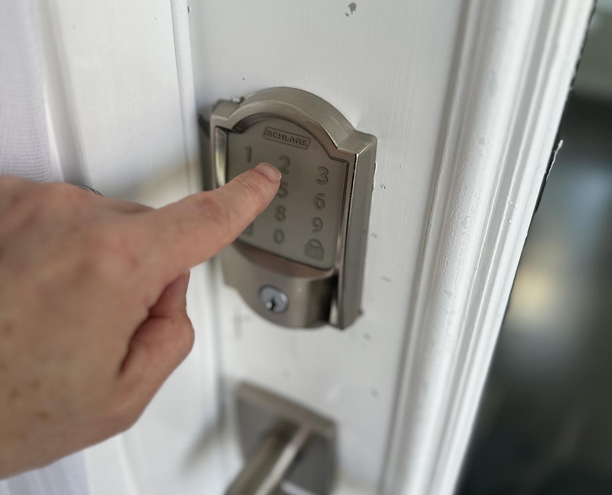 A person using the keypad on the Schlage Encode Smart Wi-Fi Deadbolt to unlock a door.