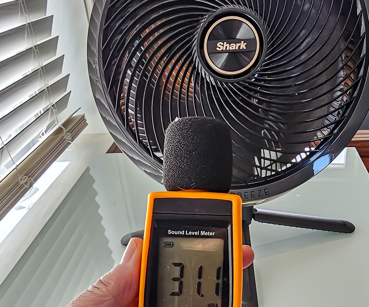 A person holding a decibel reader next to the Shark FlexBreeze Fan with InstaCool during testing.