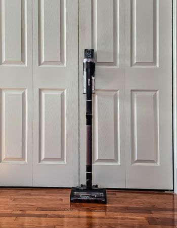 The Dyson Outsize cordless vacuum leaning against closet doors before head-to-head testing of Dyson vs Shark.