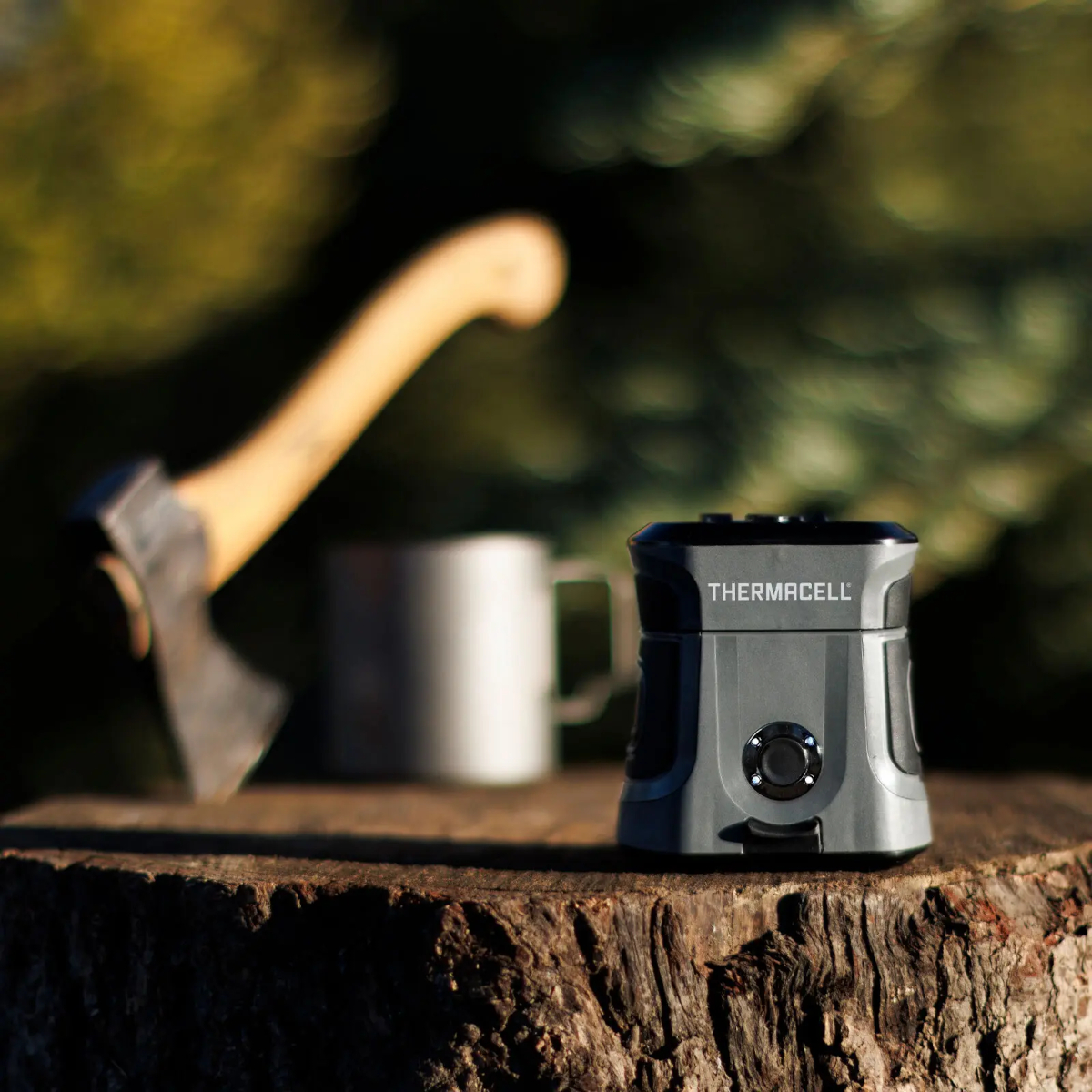 A small Thermacell Mosquito Repellent unit sitting on a tree stump outdoors.