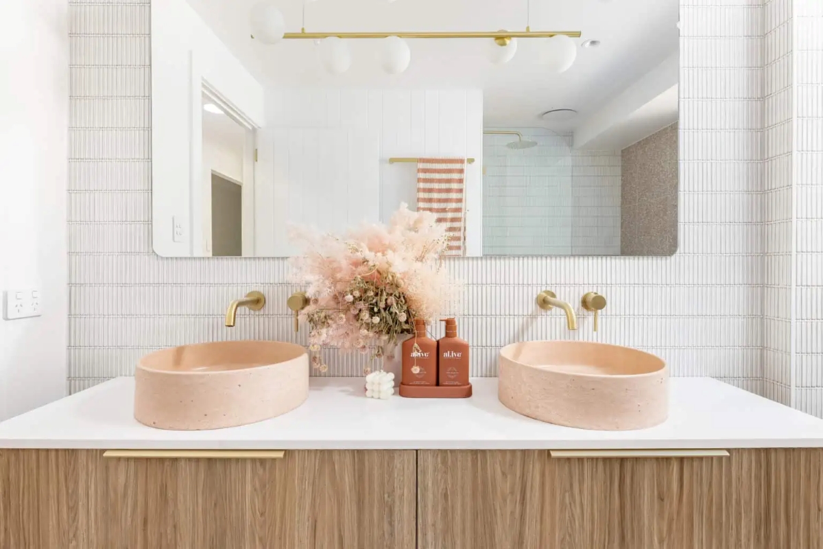 Bathroom with gold fixtures and pink stone sinks.