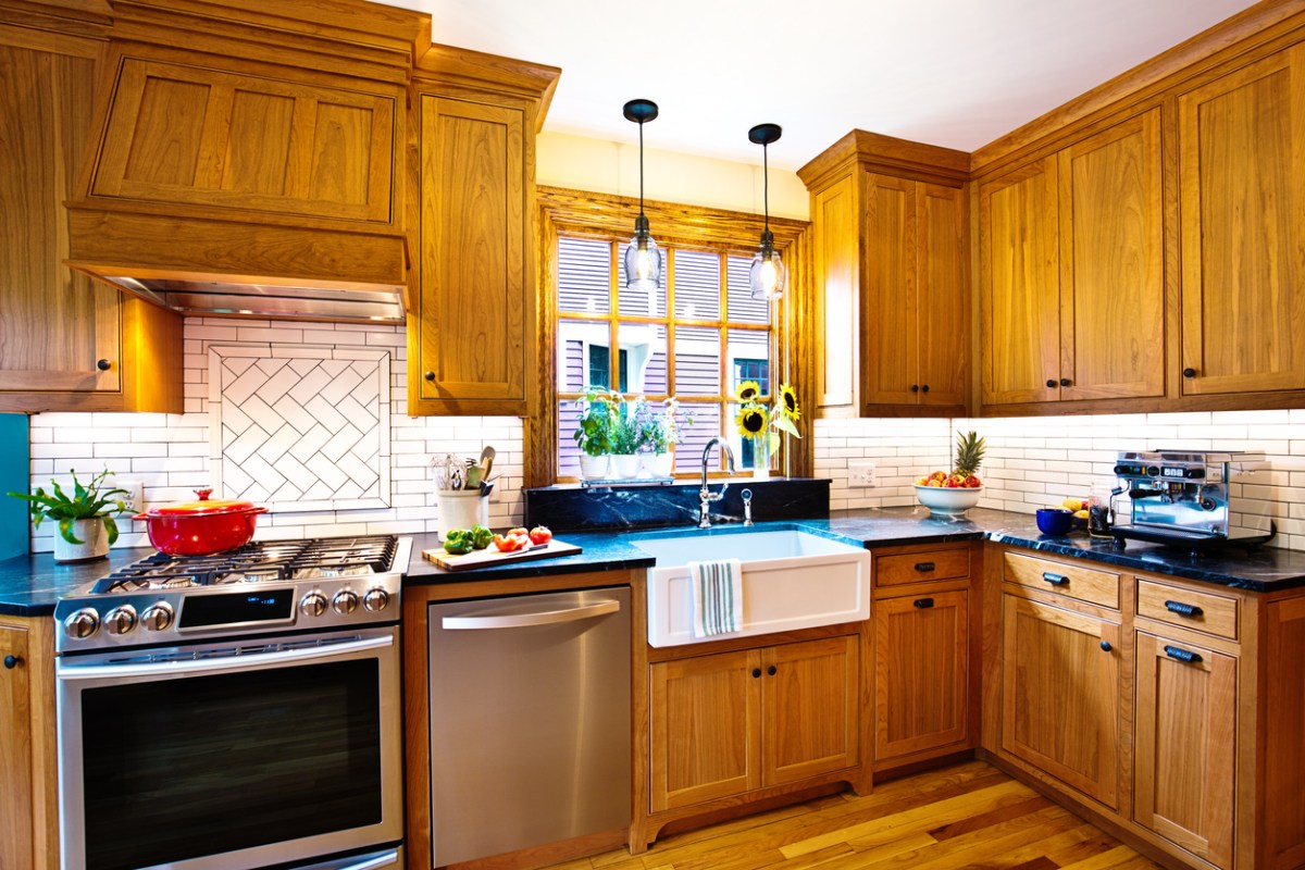 Kitchen with white backsplash, a large window, and beautiful hardwood cabinets.