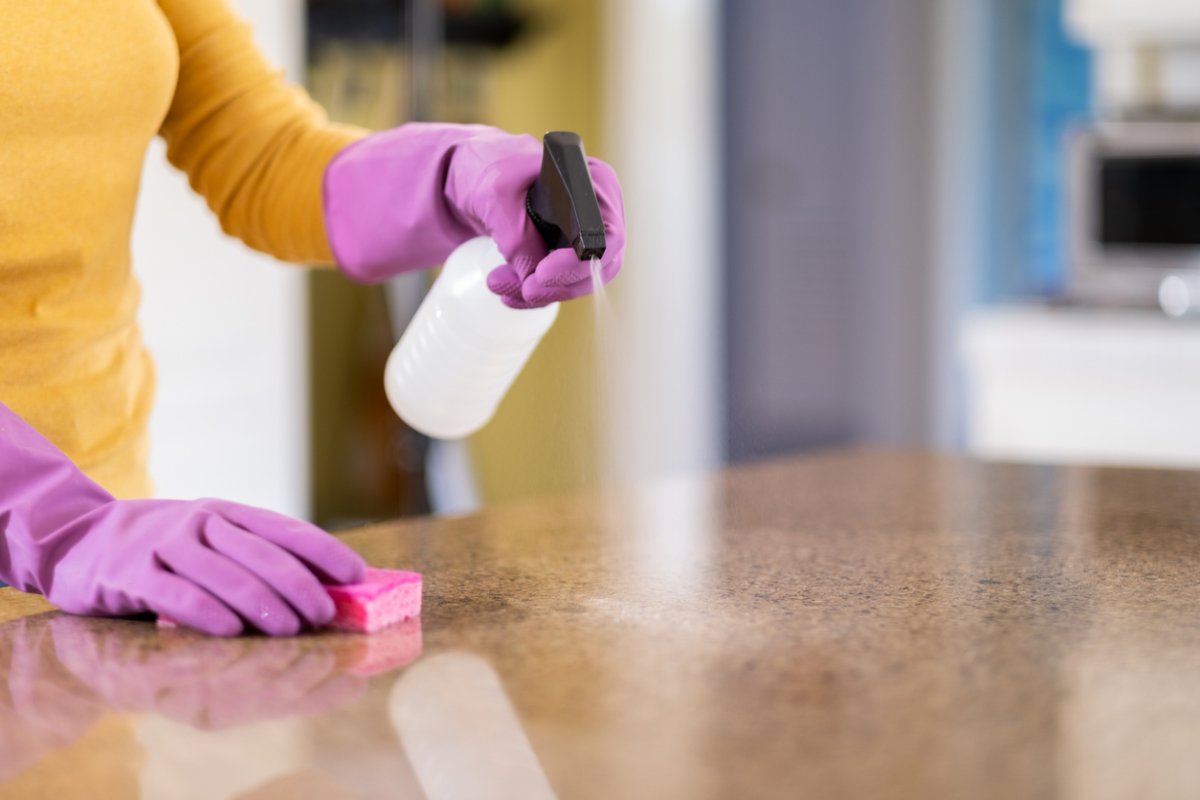 A person spraying a kitchen counter with a spray bottle.