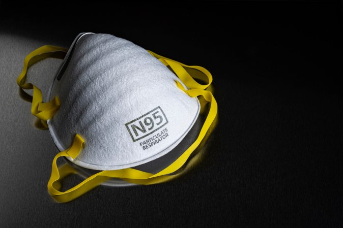 An-N95-respirator-mask-sits-on-a-black-tabletop.
