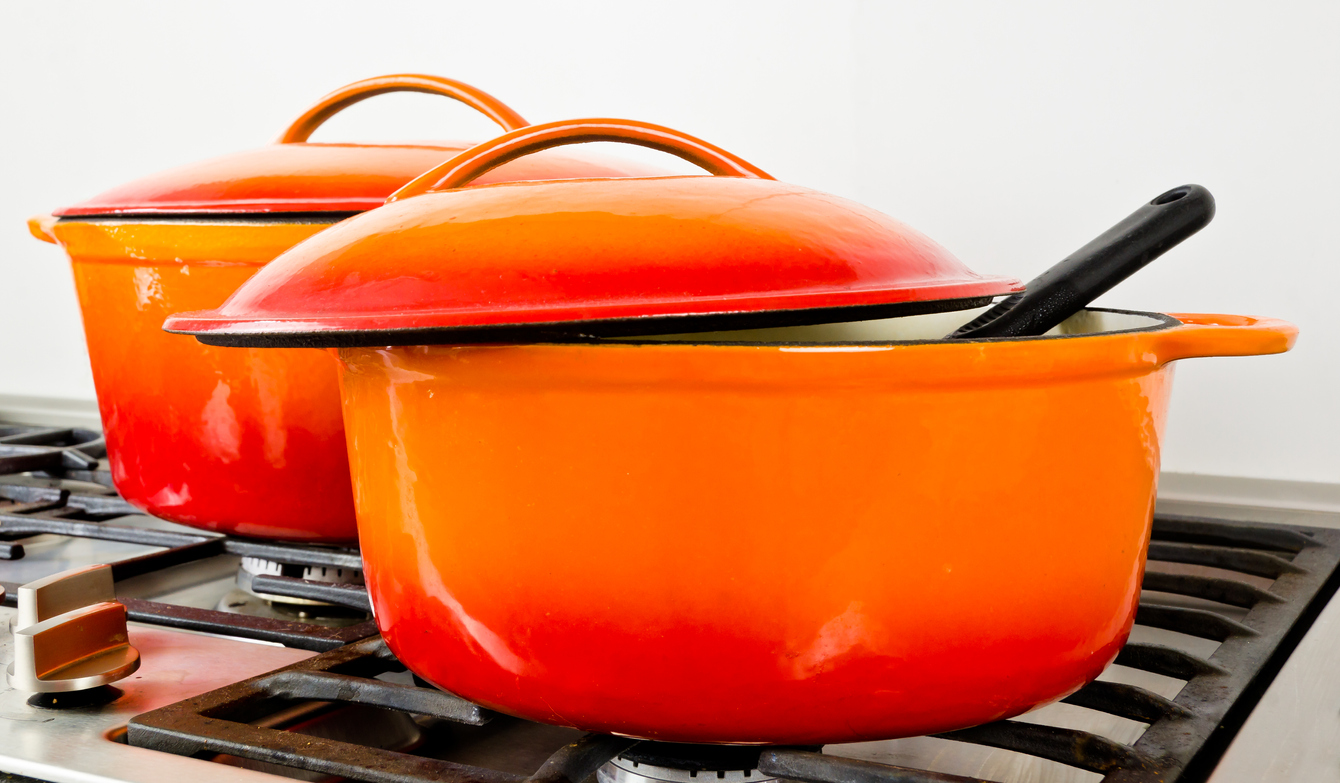 Two bright orange enamel Dutch oven pots.