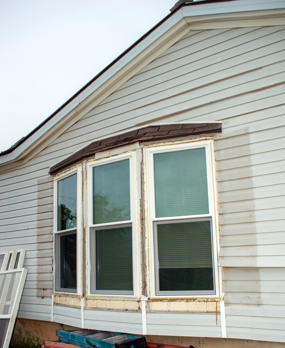 The-side-of-a-house-is-being-repaired-with-window-trim-and-warped-siding.