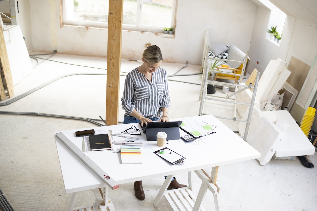 A person standing at a table documenting remodeling expenses for tax credits and deductions.