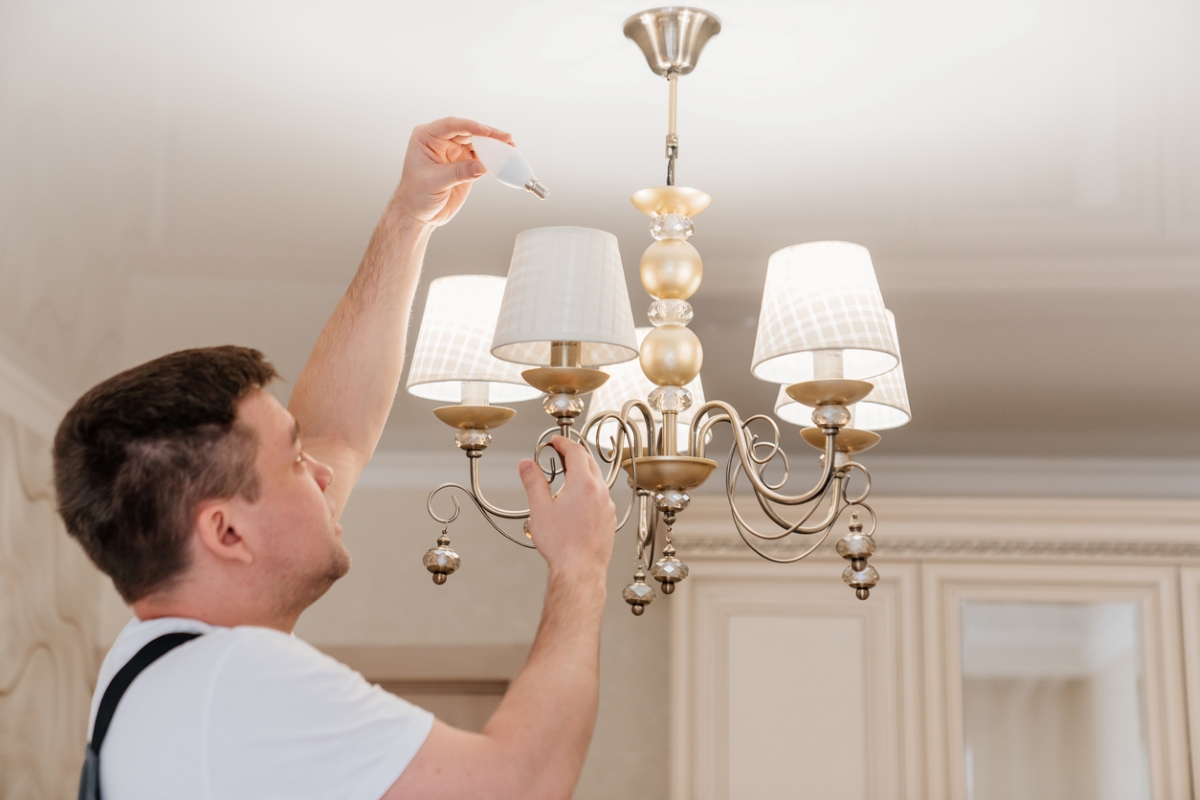 Male changing light bulb in vintage ceiling light.