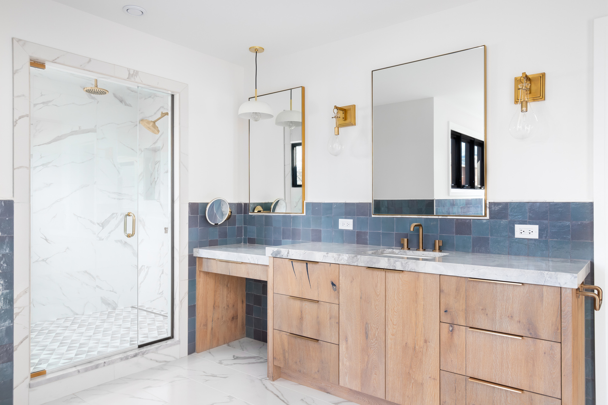 Large bathroom with blue and white tile, a double wooden vanity, and brass fixtures.