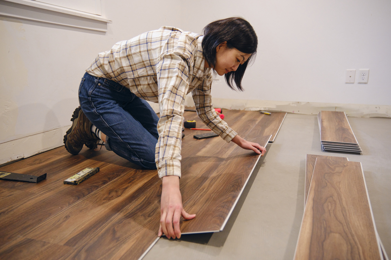 Young woman installs laminate flooring in home.