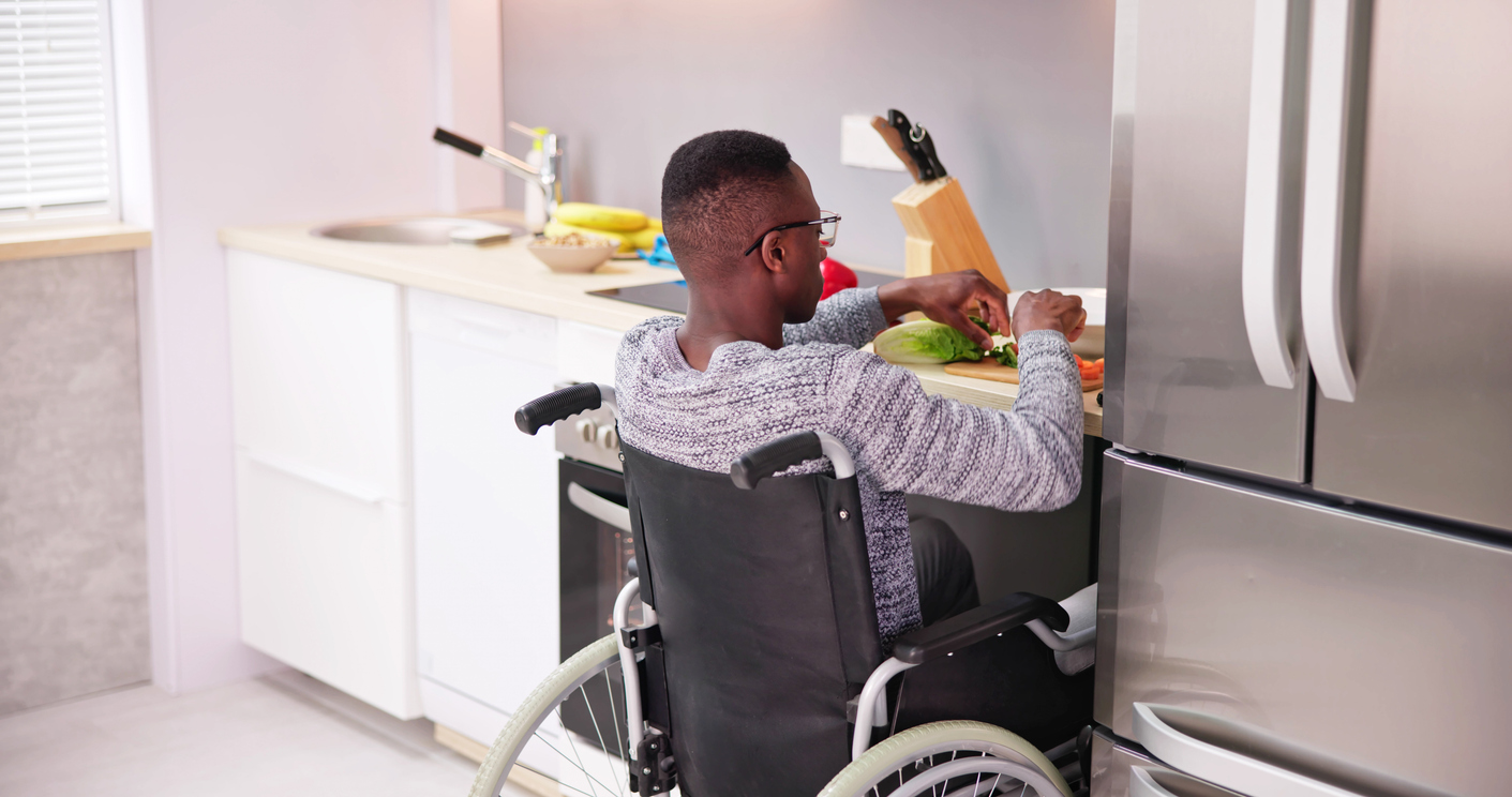 A-person-sits-in-a-wheelchair-that-pulls-under-a-kitchen-counter-while-preparing-food.