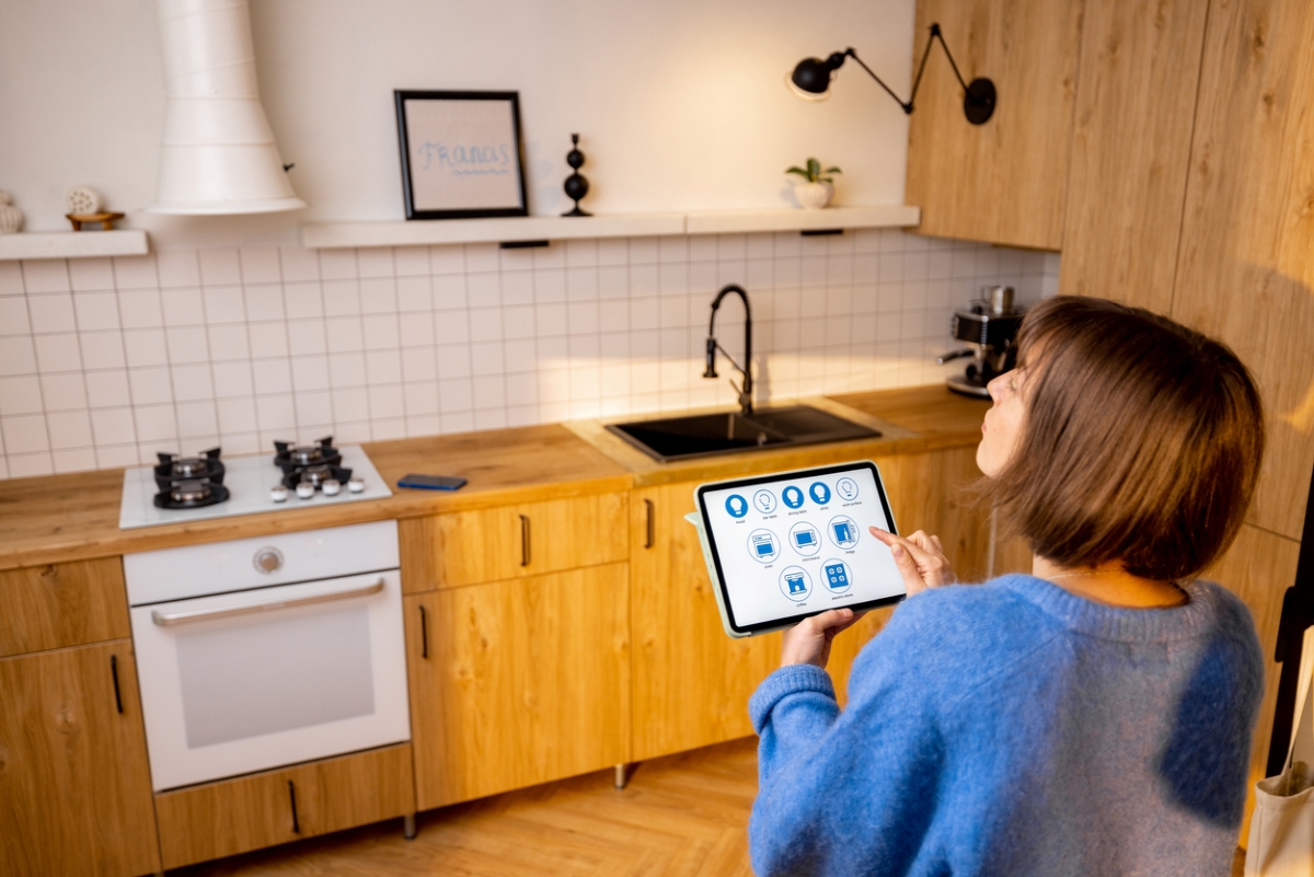 Woman using tablet to control kitchen appliances.