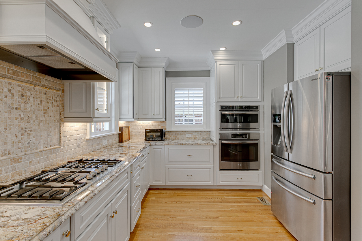 White kitchen cabinets with granite countertops and stainless steel appliances.