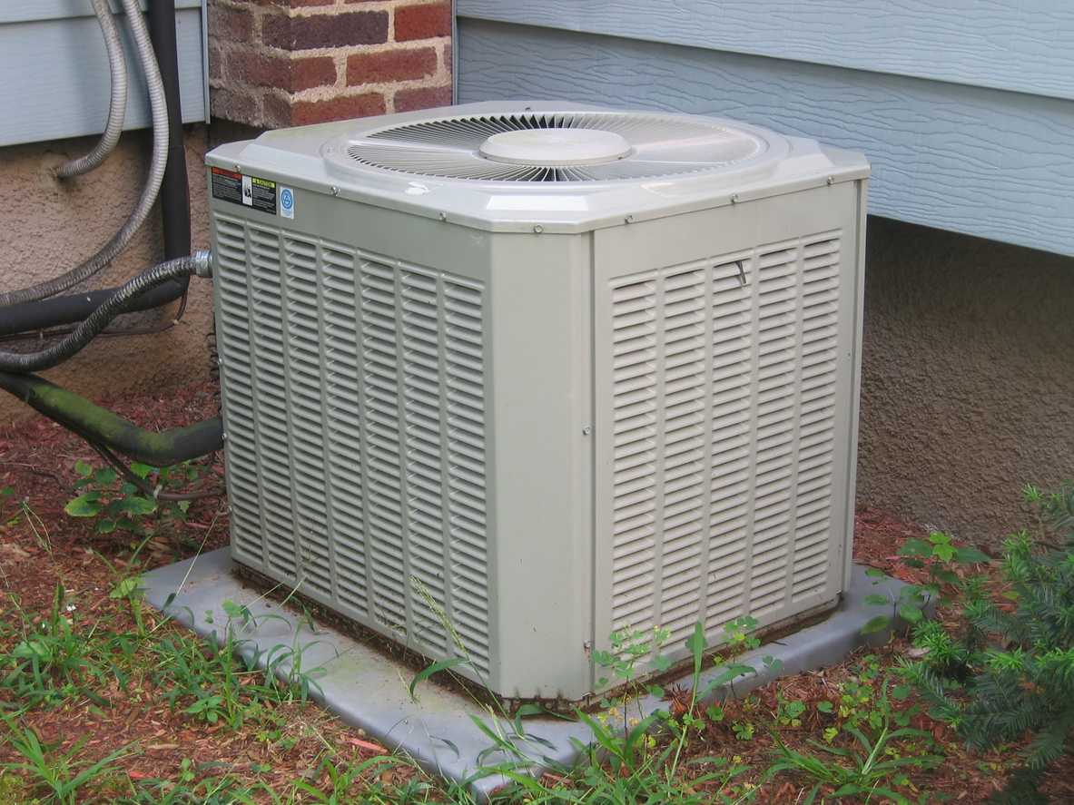 A-small-air-conditioning-unit-sits-outside-next-to-the-siding-of-a-house.