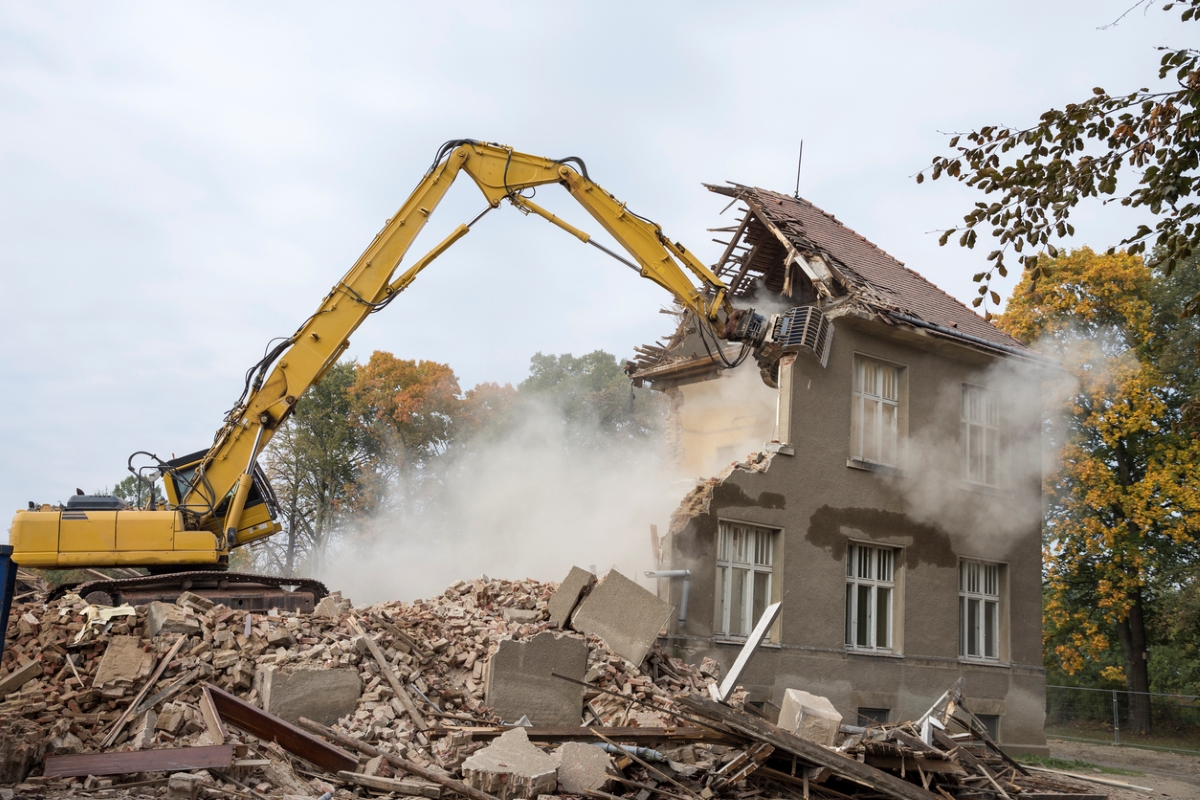 Large digger demolishing house.