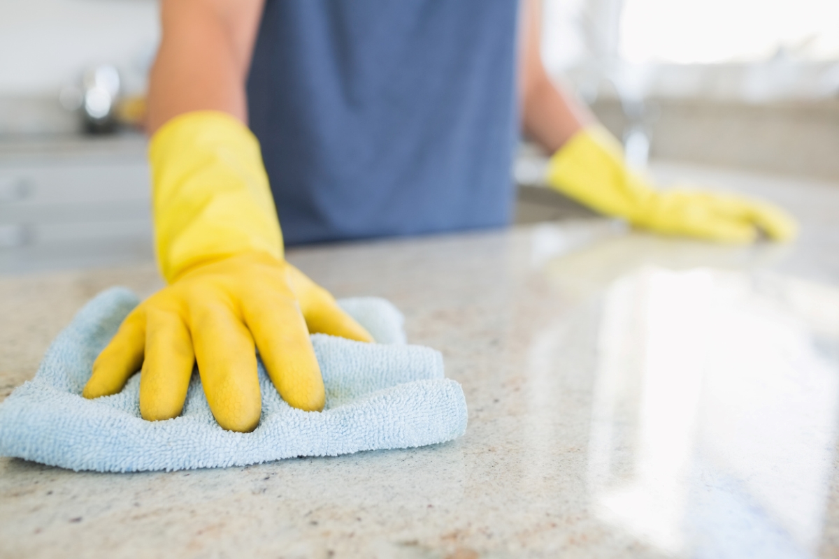 Person with yellow gloves wiping down counter.