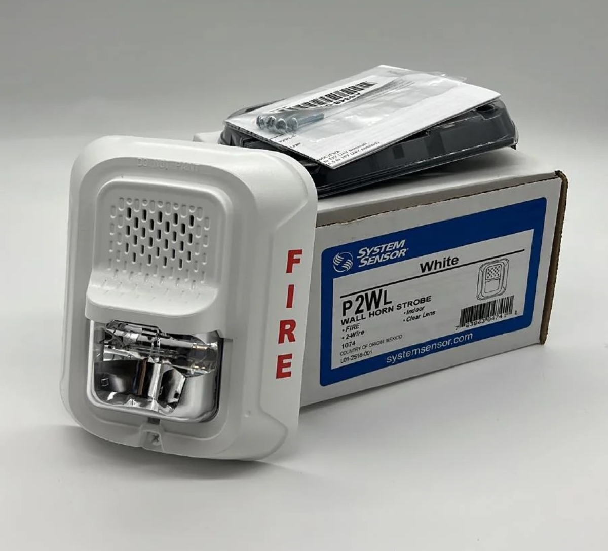 Fire alarm with strobe next to packaged box.
