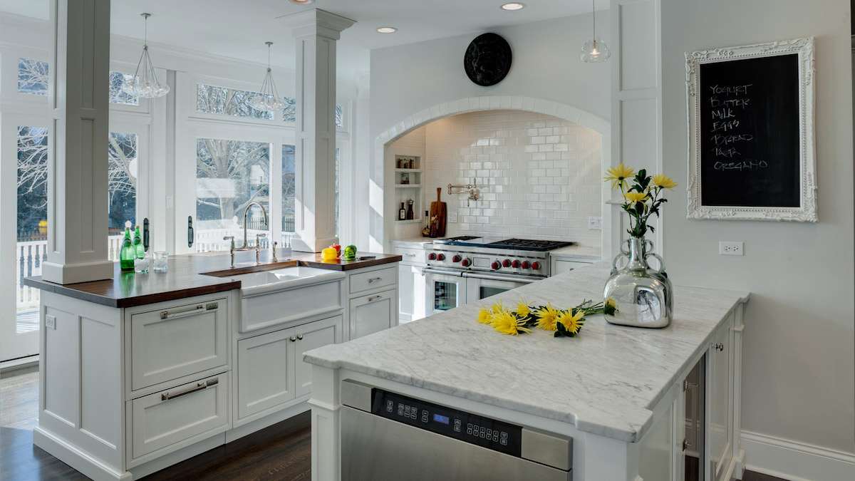 A white kitchen featuring a hidden range hood and a blackboard with a grocery list.