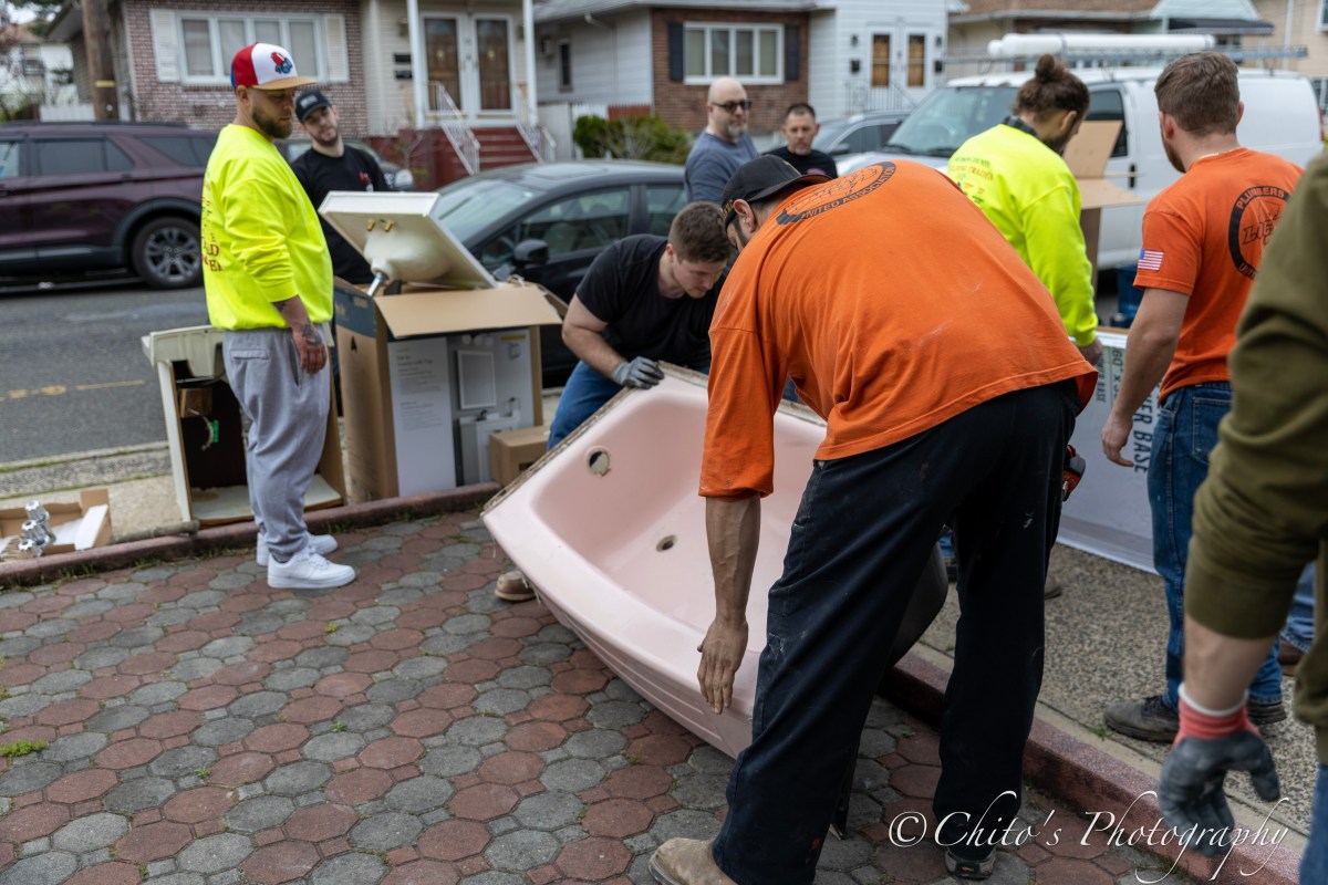Volunteers help to move a new bathtub into a house in Jersey City.