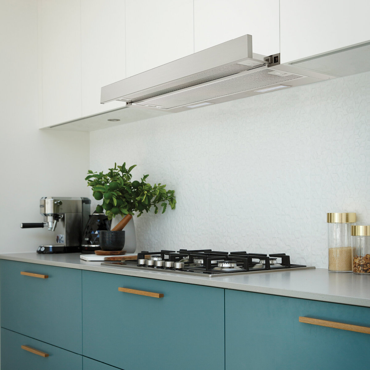 A slide-out range hood in a white and teal kitchen.