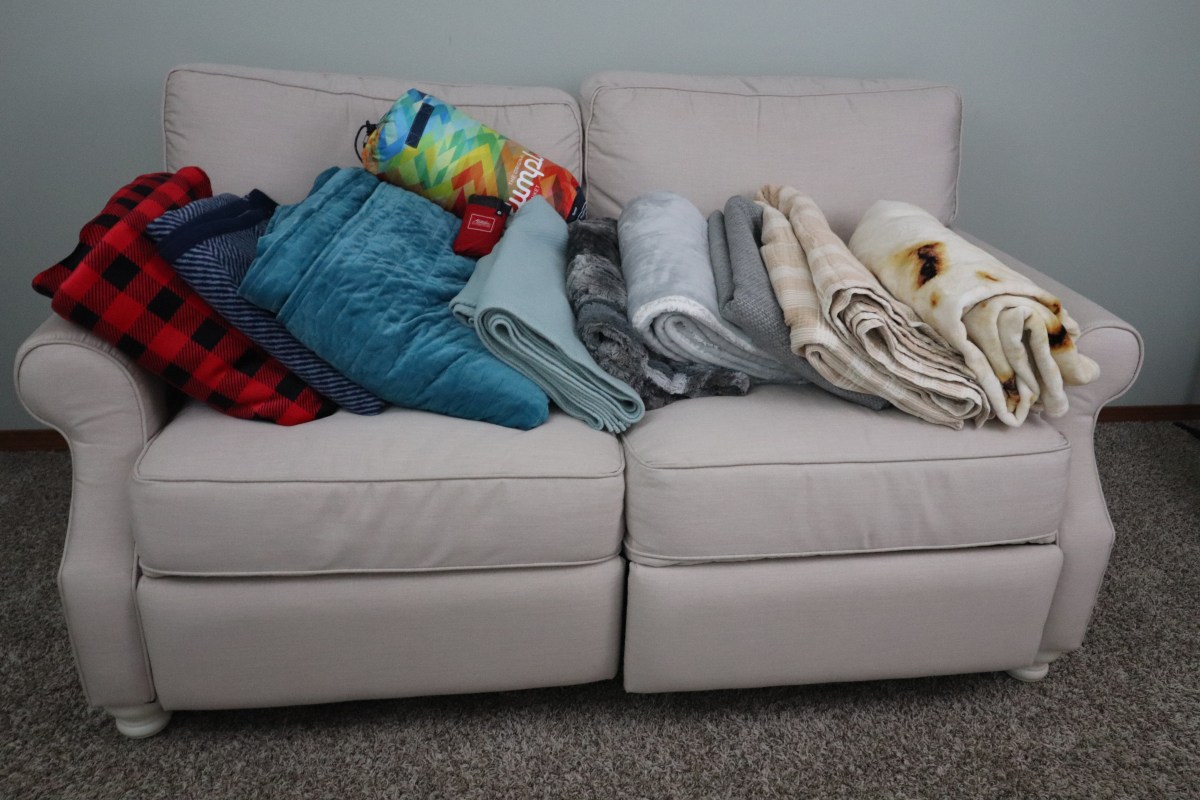 A group of the best blankets folded on a couch before testing.