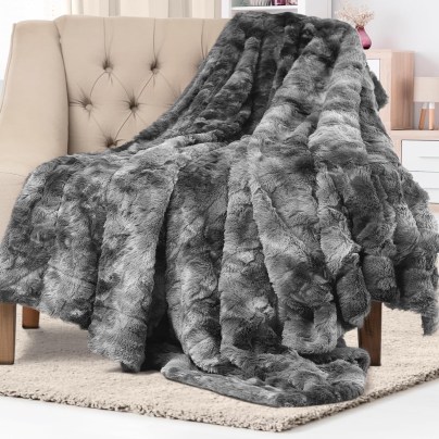 The Everlasting Comfort Luxury Faux Fur Throw Blanket draped over the arm of a chair.