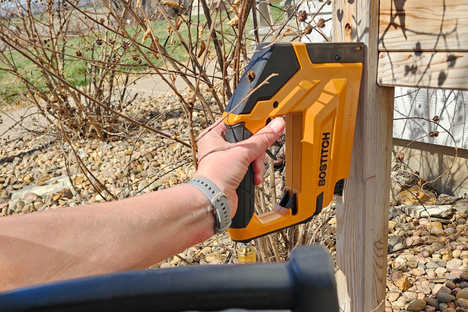 A person using a Bostitch crown stapler outdoors during testing.