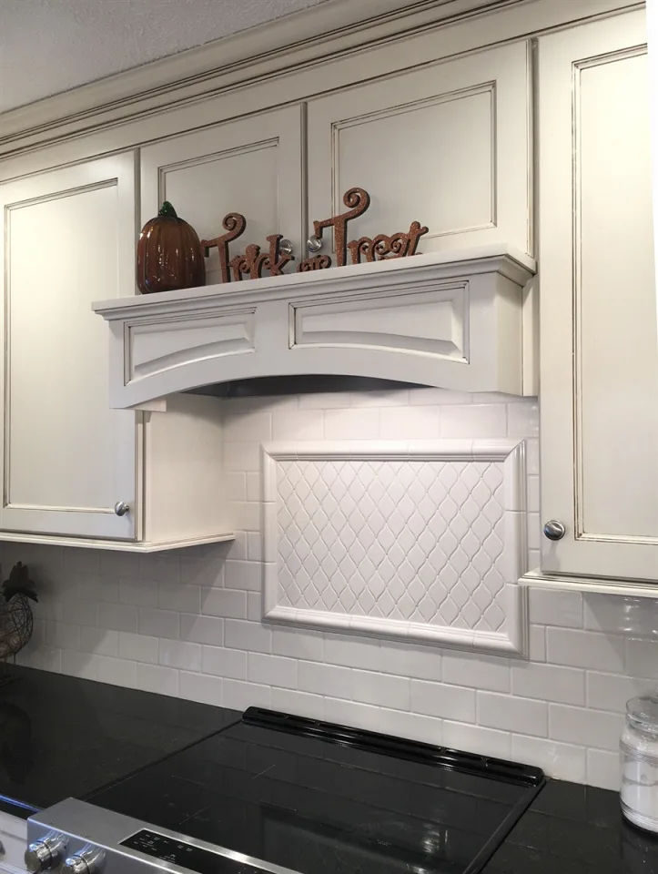 A covered range hood functioning as a shelf for Halloween decor in a white kitchen.