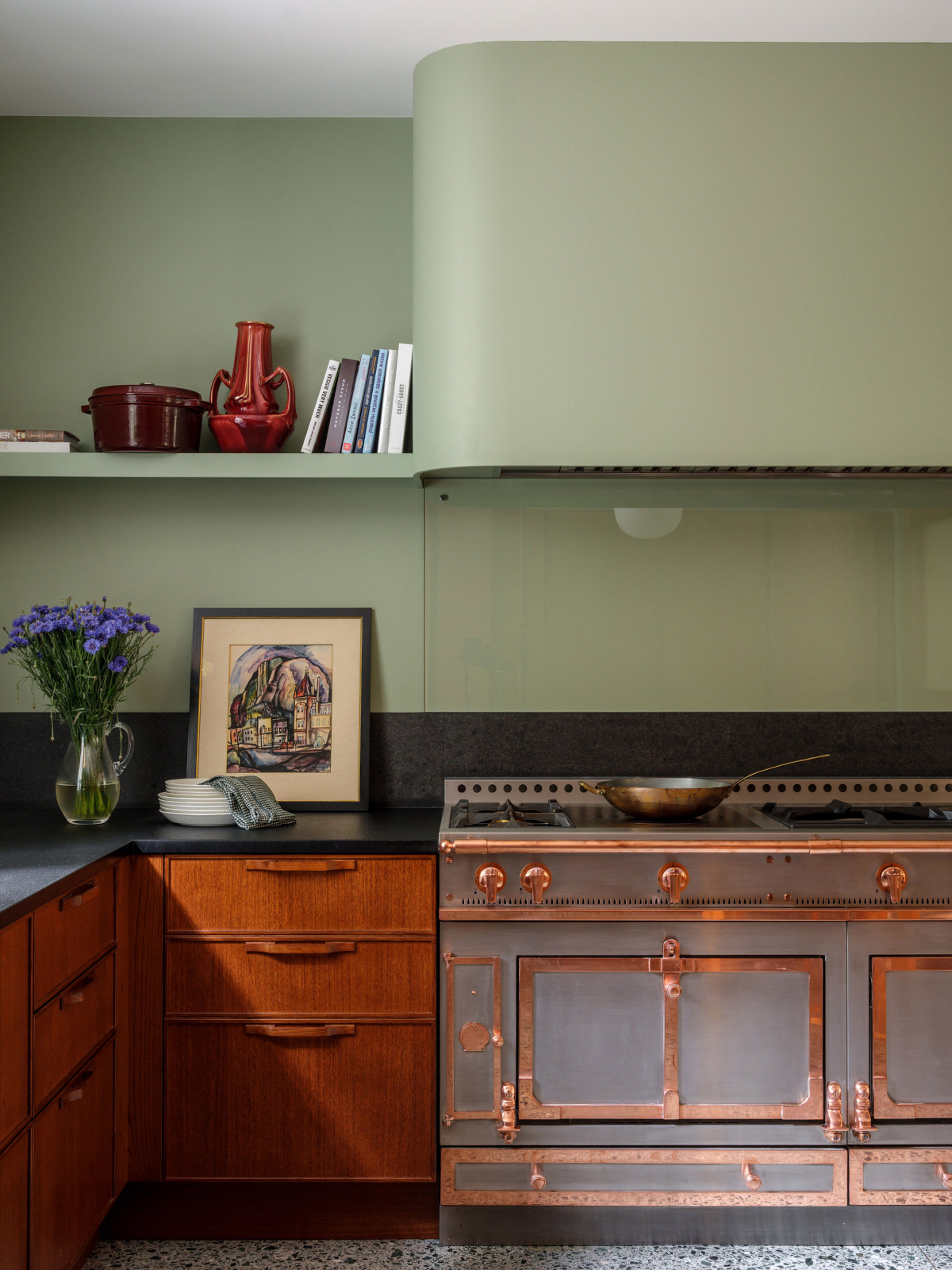 A curved olive range hood in a custom retro themed kitchen.