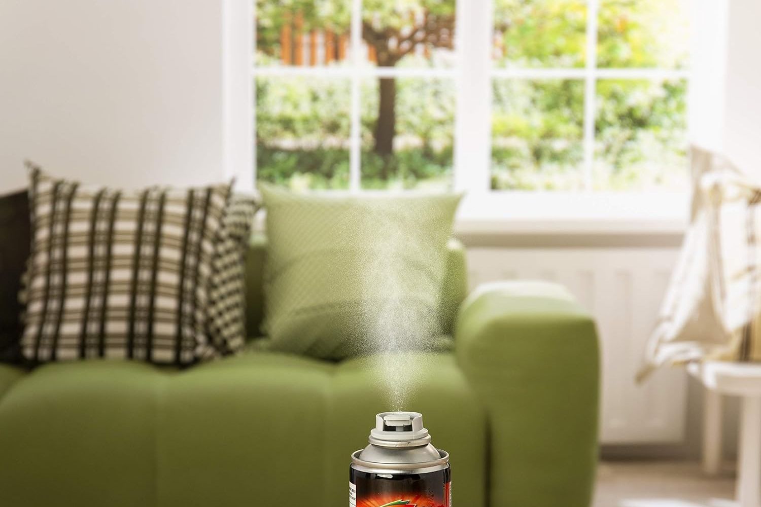 A close up of a flea bomb can being sprayed in a living room.