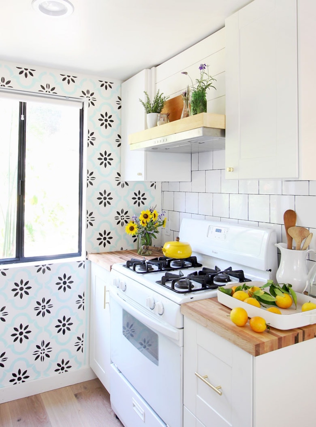 A ductless range hood is below open shelving in a kitchen to display plants, and decor.