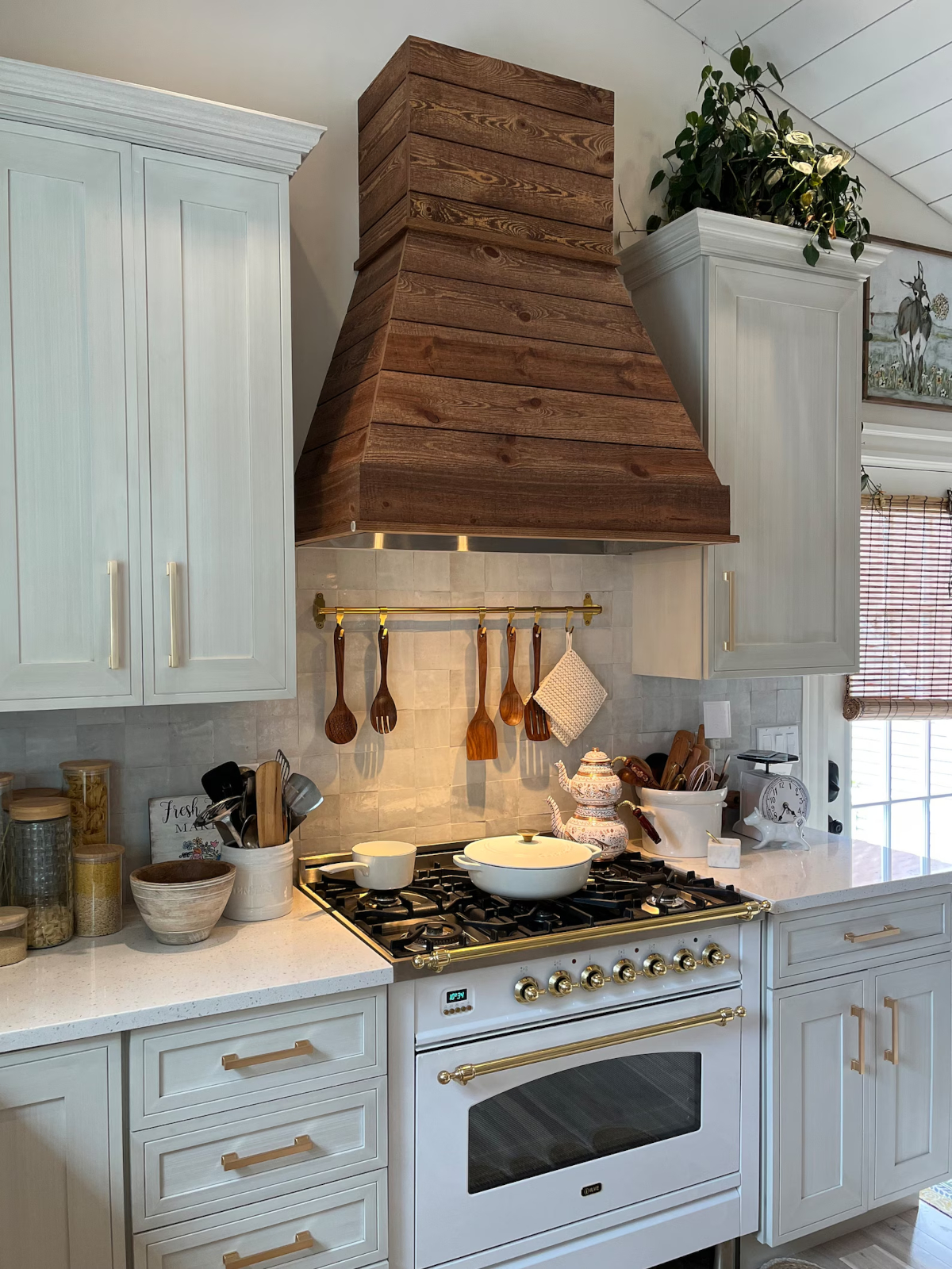 A faux wood range hood with gold trim in a farmhouse-themed kitchen.