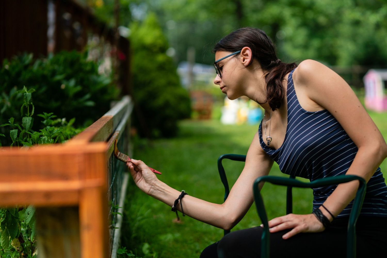 A woman paints a fence. 