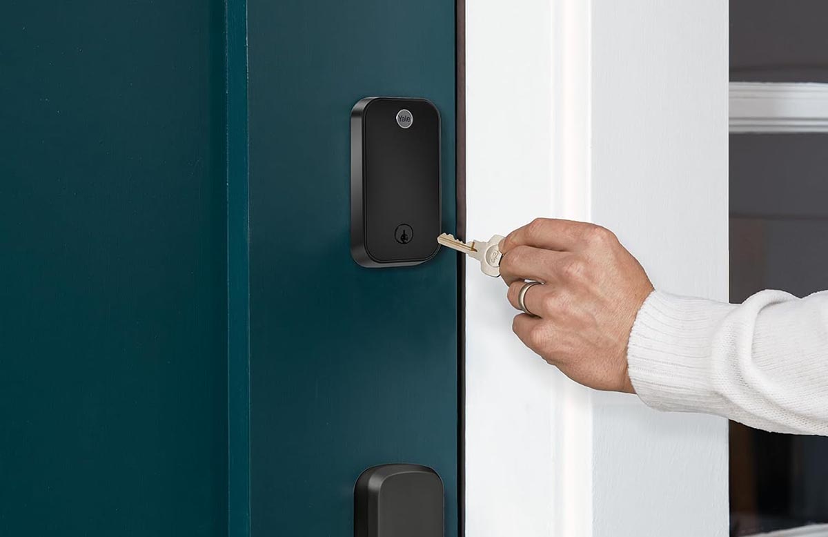 A close up of a person's hand putting a key in a smart lock. 