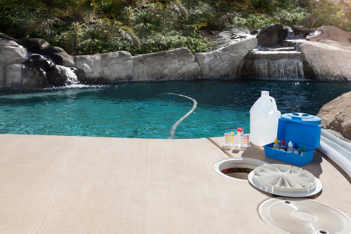 Pool cleaning supplies are seem in front of a pool.