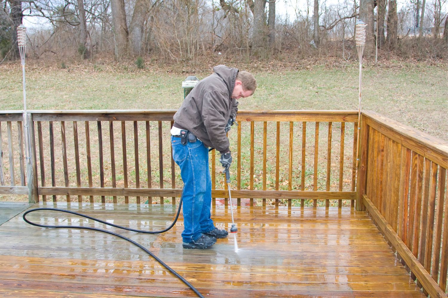A person pressure washes a deck.