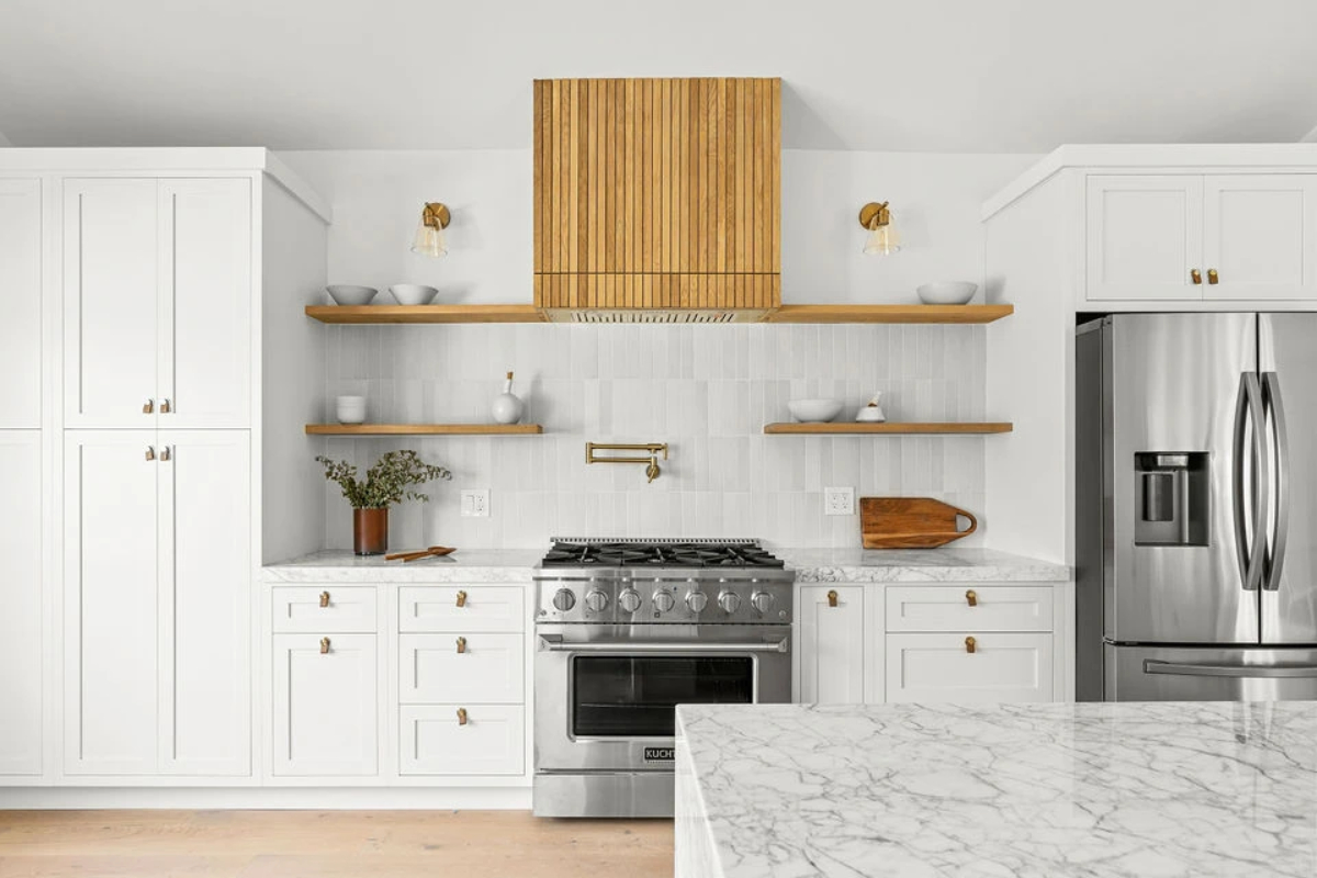 An oven range hood with a light-colored wood slat finish in a white theme kitchen.