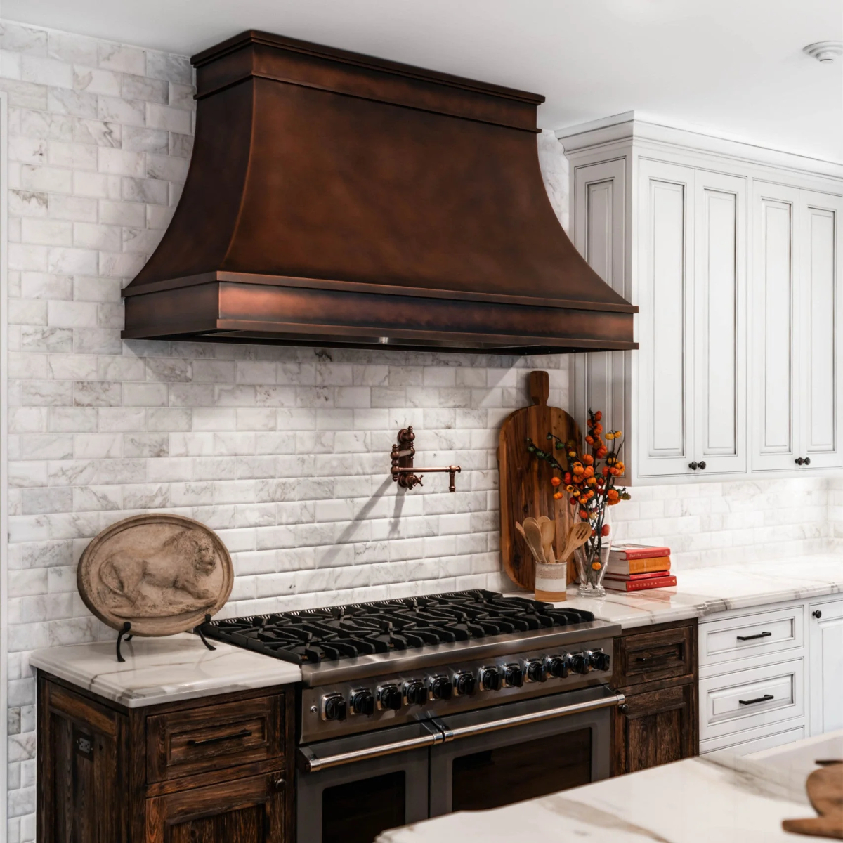 A rubbed copper oven range hood in a white and copper themed kitchen.