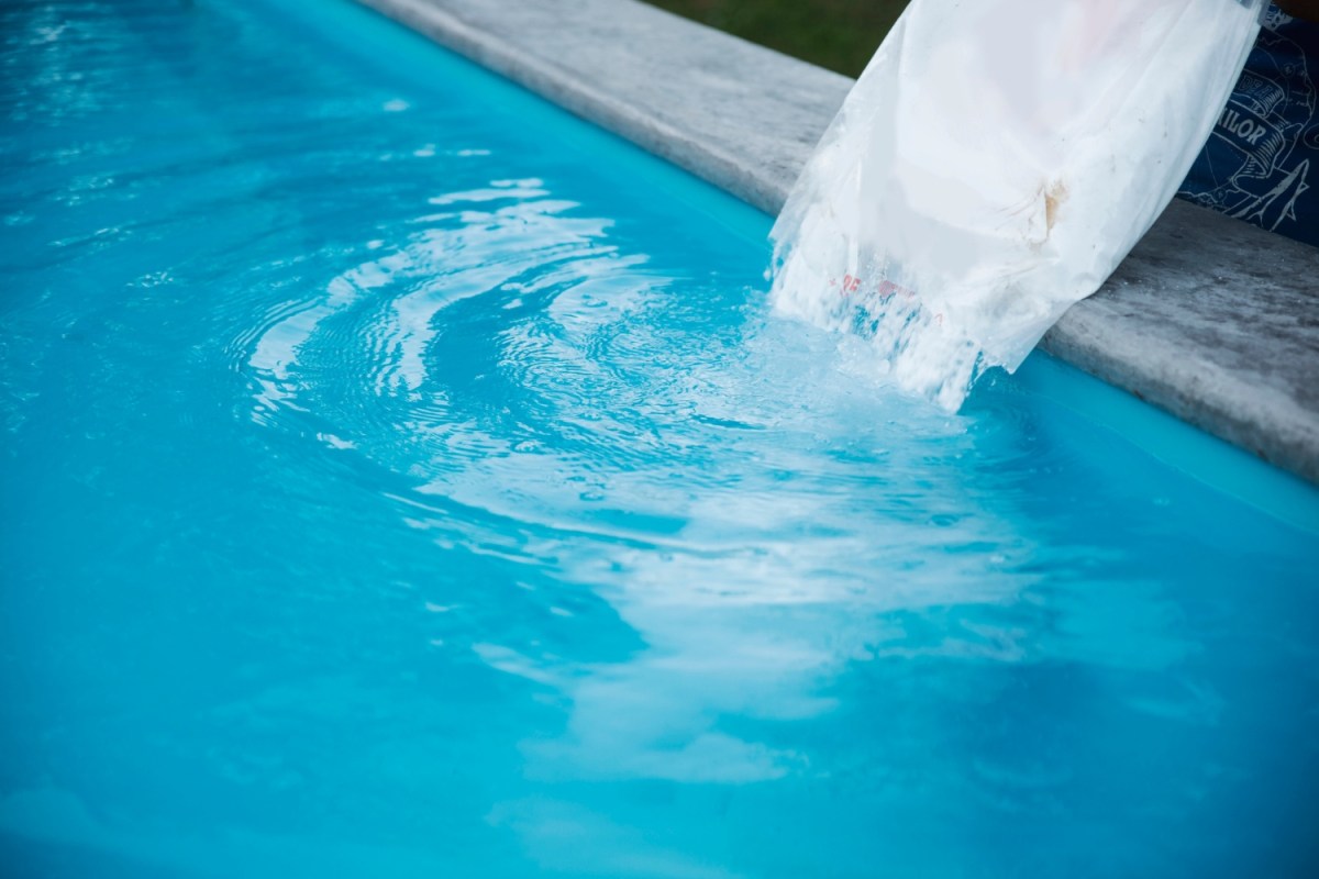 A close up of a solution being poured into a pool. 