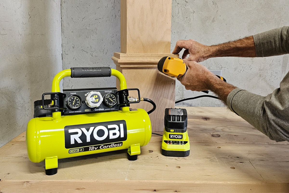 A person using the Ryobi One+ 18V Cordless 1-Gal. Air Compressor Kit to attach molding during testing.