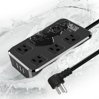 The APS IPX6 9-in-1 Outdoor Power Strip with water splashing on it.