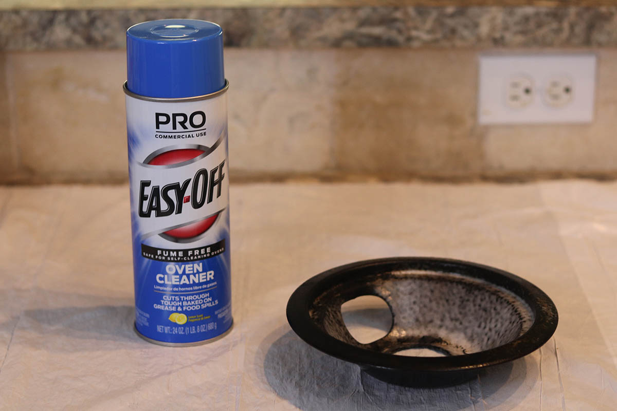 A can of Easy-Off Fume-Free Oven Cleaner next to a burner cap during testing.