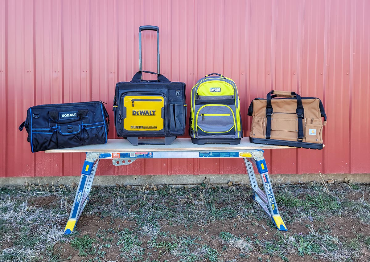 Several of the best tool bags on a workbench outdoors before testing.