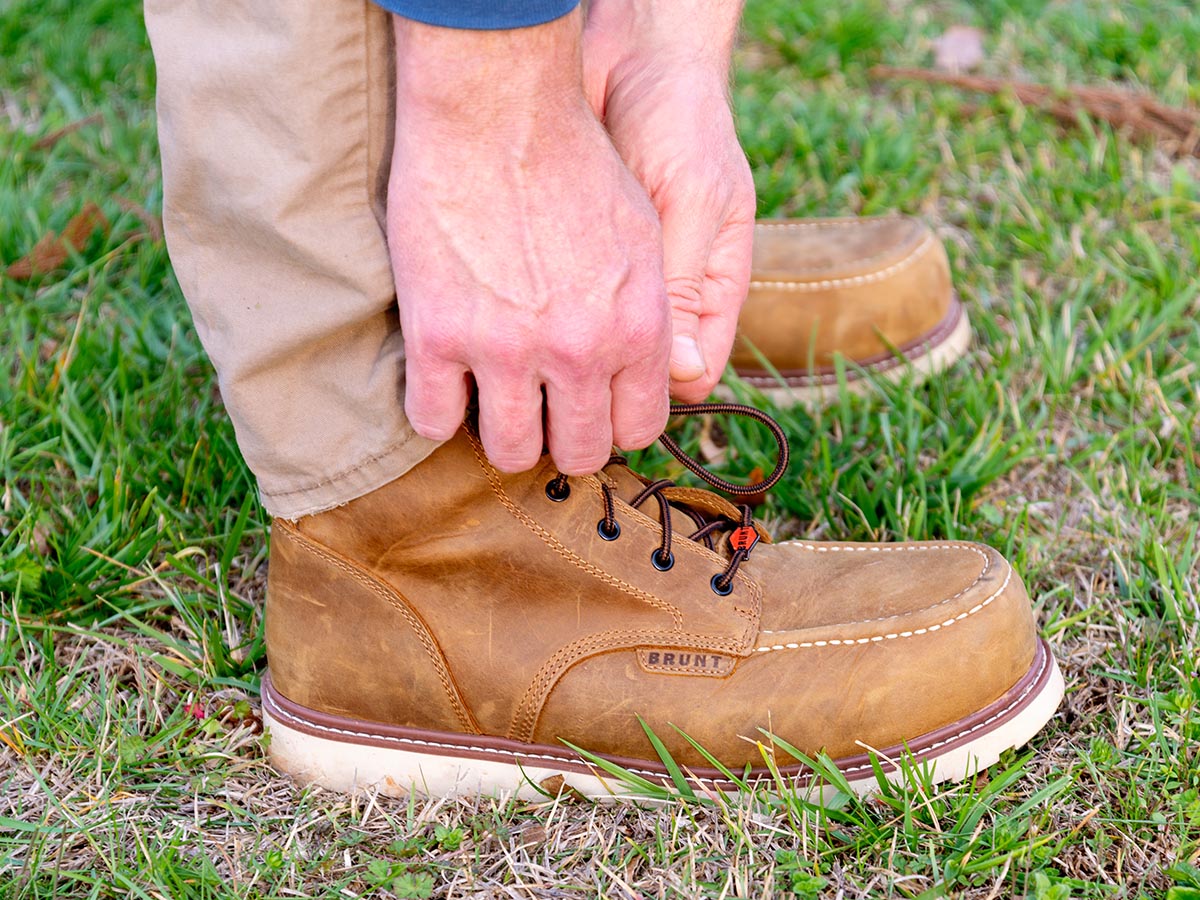 A person tying the laces on the best work boots during testing.