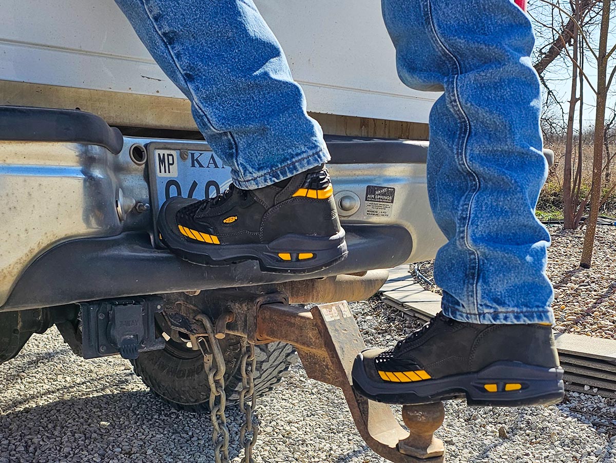 A person stepping up onto a hitch ball while wearing the Keen Troy 6" Waterproof Carbon-Fiber Toe Boot during testing.