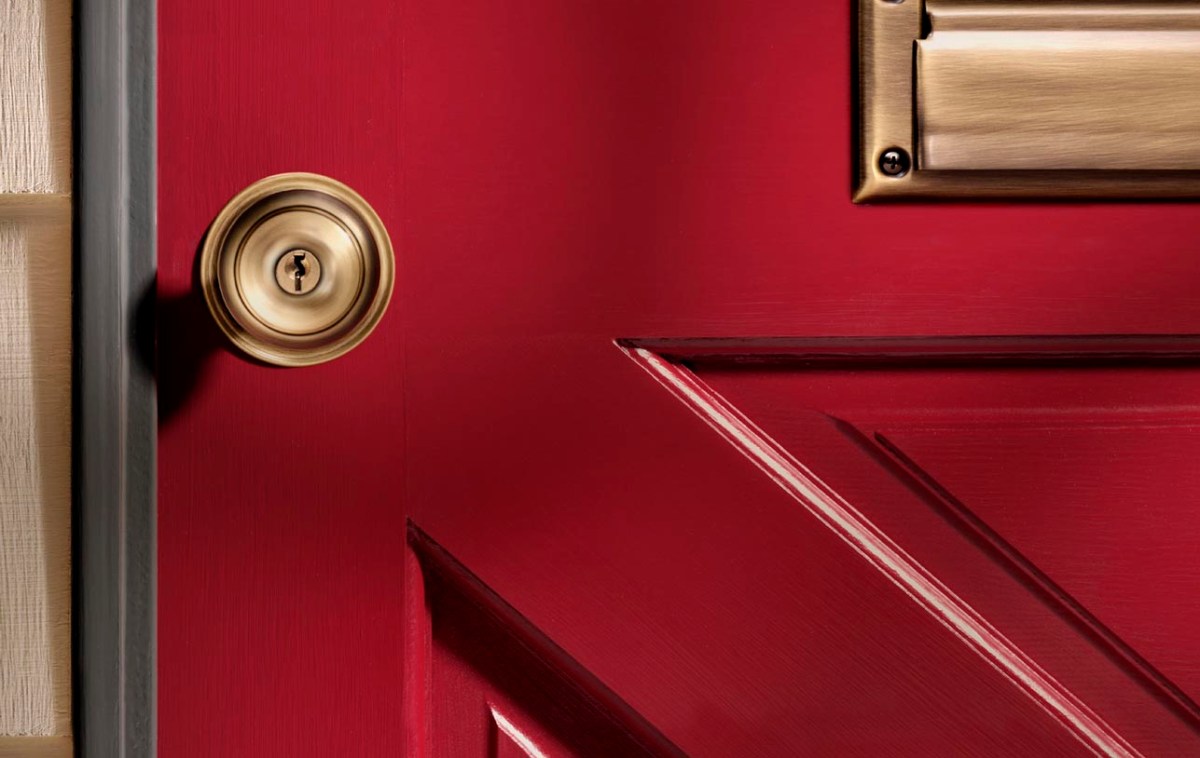A close up of a brass door knob attached to a red door.