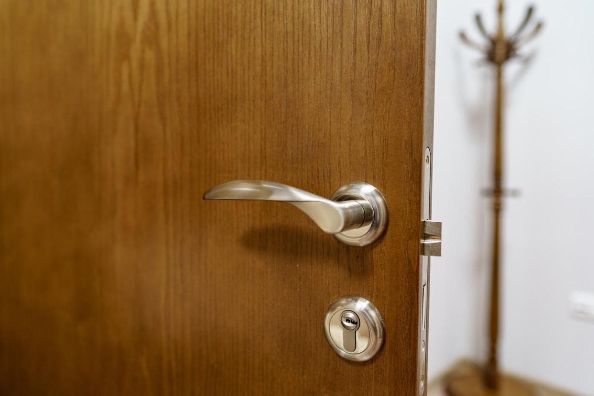 A close up of a door handle in a brown door. 