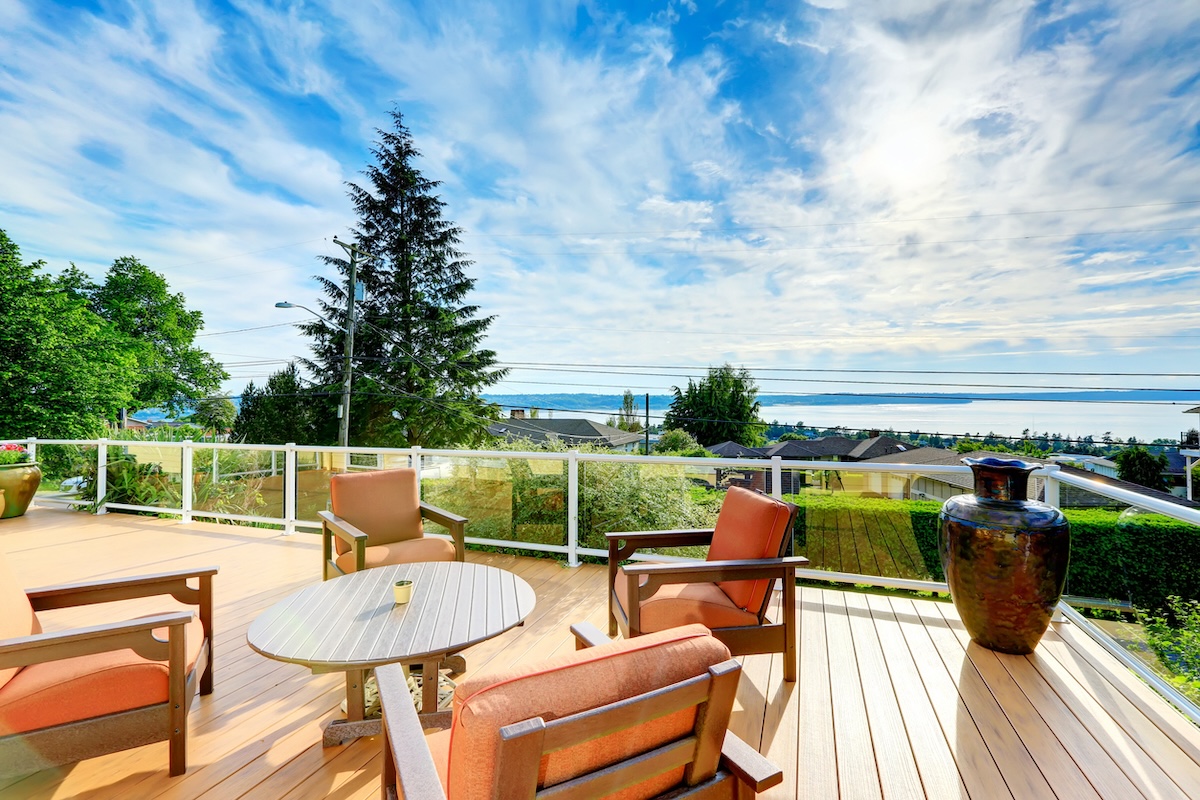 A home deck with patio furniture and a lakeside view.