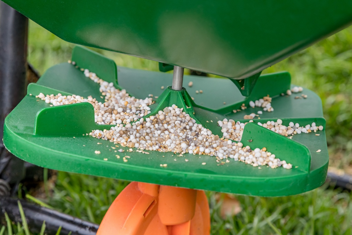 Close view of granular herbicide in a green fertilizer spreader. 